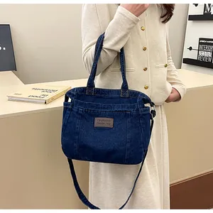 Detail view of dark blue denim tote bag with leather tag and multiple utility pockets