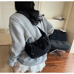 Retro black denim dumpling bag styled on shoulder with vintage knot detail and wide strap