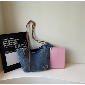 Close-up of washed denim tote bag with thick woven rope handles and metal patch detail
