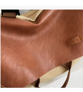 Close-up of brown leather and khaki canvas textures with black zipper and woven strap