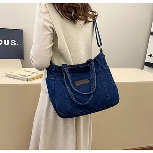 Detailed view of dark blue denim tote bag with leather patch and adjustable strap
