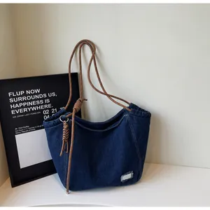 Close-up of deep blue denim tote bag featuring rustic rope handles and frayed woven patch