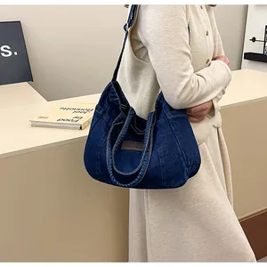 Detail of dark blue denim tote bag featuring vintage leather patch and contrast stitching