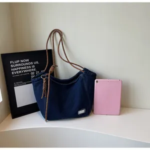 Detail of blue denim tote bag with brown woven rope strap and drawstring design