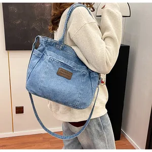 Close-up of vintage blue denim tote bag with brown leather label and side pocket texture
