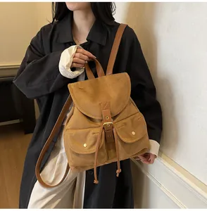 Détail du sac à dos vintage en daim marron avec poches frontales et boucles en métal
