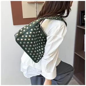 Λεπτομέρεια σκούρα πράσινη τσάντα ώμου με ασημένια πανκ τρουκς φορεμένη από μοντέλο