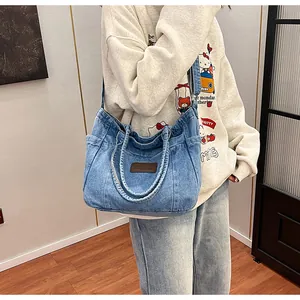 Detail view of denim tote bag with brown leather patch and side pockets for storage