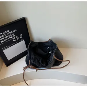 Detailed interior view of denim tote bag showing black lining and brown rope handle