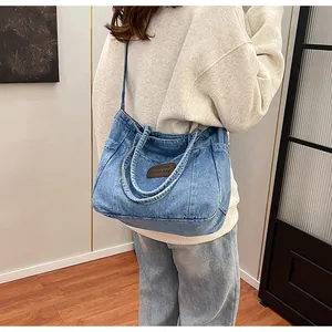 Detail of blue denim tote bag with leather patch and washed canvas texture on light wood background