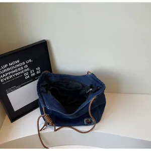 Deep blue denim tote bag showing interior lining, zipper pockets and woven rope handle