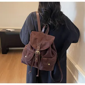Vue détaillée d'un sac à dos vintage en daim marron avec boucles dorées et poches avant