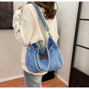 Detail of light blue denim tote bag with brown leather patch on a female model