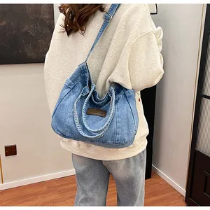 Adjustable crossbody strap and leather logo detail on washed blue denim tote bag