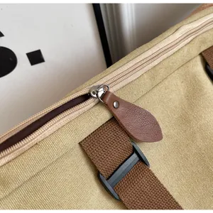 Detail of khaki canvas tote with brown leather zipper pull and silver metal zip closure