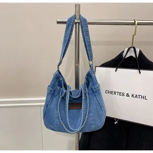 Detail of blue denim tote bag with leather tag and spacious side pocket for storage
