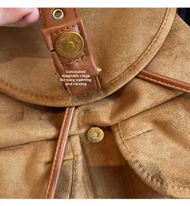 Détail de la boucle magnétique cachée et des ferrures dorées sur le sac à dos brun