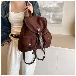 Detail of dark brown faux suede backpack featuring front rivet pockets and flap closure