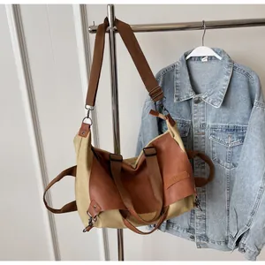 Detail of canvas tote bag showing adjustable brown leather strap and metal hooks
