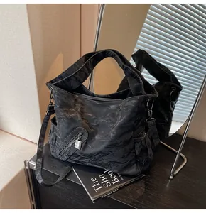 Λεπτομέρεια μαύρης τσάντας tote με vintage πλισέ υφή και λειτουργικές τσέπες με φερμουάρ