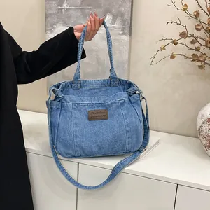 Blue denim tote bag with brown leather label and adjustable shoulder strap for women