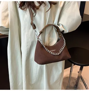 Dettaglio borsa sottospalla in pelle scamosciata marrone scuro con catena d'argento su modella
