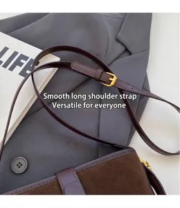 Close-up of adjustable long strap and smooth matte leather texture on dark brown bucket bag