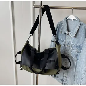 Detail of olive green canvas tote bag with black faux leather trim hanging on a hanger