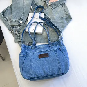Light blue denim tote bag with brown leather label and shoulder strap on white background