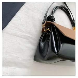 Detail of the contrast patchwork bag with glossy black body and matte brown flap cover