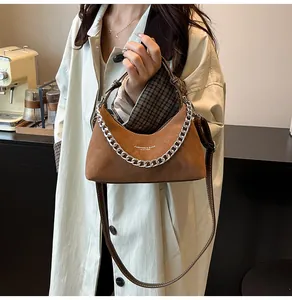 Dettaglio borsa hobo in pelle scamosciata marrone con catena in metallo e tracolla in pelle