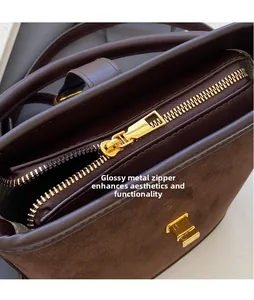 Détail macro du zip en métal doré lisse sur le sac seau en daim marron foncé