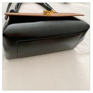 Detailed close-up of the black and brown leather handbag with elegant gold metal lock