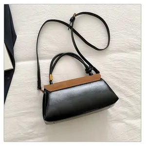 Detail of vintage square bag with brown suede flap and black glossy finish and knot handle