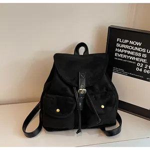 Détail d'un sac à dos en daim noir avec fermeture à cordon et boucles dorées
