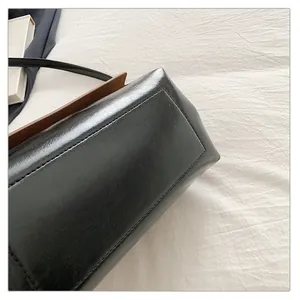 Detail view showing bottom stitching and side leather texture of black square shoulder bag