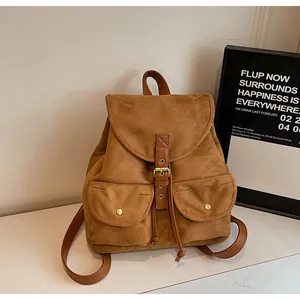 Détail d'un sac à dos vintage en daim marron avec poches à rabat et boucles dorées chic