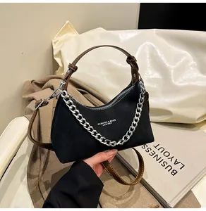 Dettaglio borsa vintage nero opaco con catena d'argento e tracolla in pelle marrone
