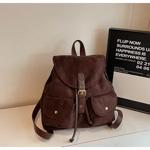Détail d'un sac à dos vintage en daim marron foncé avec poches avant et boucles en métal