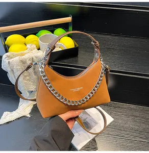 Dettaglio borsa a mezzaluna in camoscio marrone con catena d'argento e manico in pelle