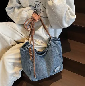 Blue distressed denim tote bag with brown rope straps and vintage wash texture