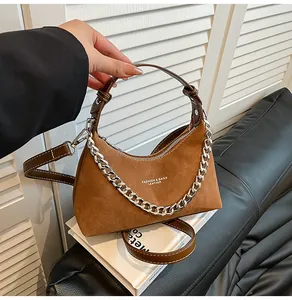 Dettaglio borsa retrò in pelle scamosciata marrone con catena d'argento e manico in pelle
