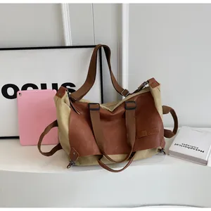 Detail of khaki canvas and brown leather tote bag with adjustable strap and metal buckles