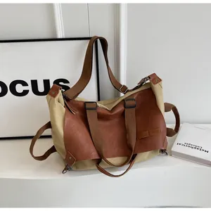 Detail of vintage canvas and brown leather tote showing wide shoulder strap and metal buckles