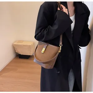Détail du sac seau en daim marron avec fermoir magnétique doré et bandoulière réglable