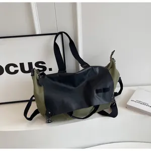 Detail view of olive green canvas tote bag showing leather flap and wide crossbody strap