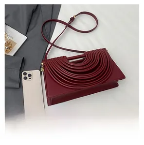Close-up of wine red woven bag with layered ribbed design and long leather strap