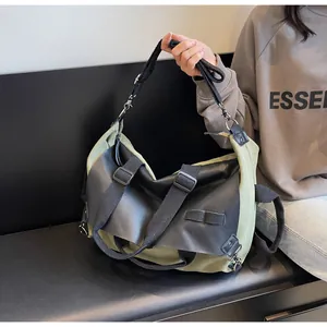 Detail of olive green canvas tote bag with black leather trim and wide nylon strap