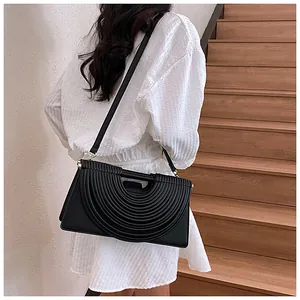 Detail of black woven shoulder bag with concentric pleated design on model back view