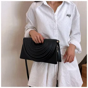 Detail of black woven evening bag with artistic circular pleats and gold hardware